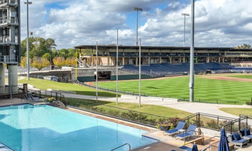 a swimming pool with chairs and umbrellas next to a large building